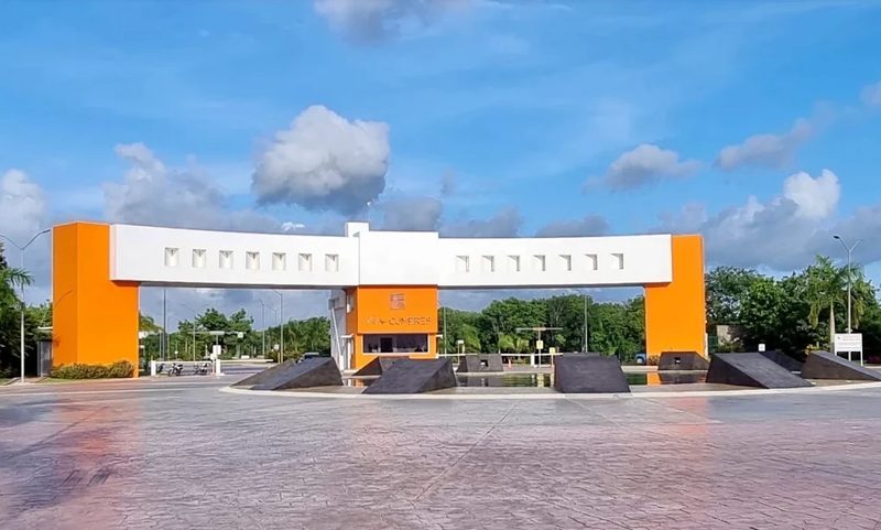 El acceso de Vía Cumbres sobre la Av. Huayacán: el arco naranja y blanco que marca la entrada al residencial.