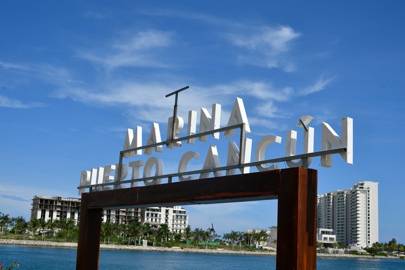 El letrero de la Marina Puerto Cancún sobre el canal, con las torres del desarrollo al fondo.