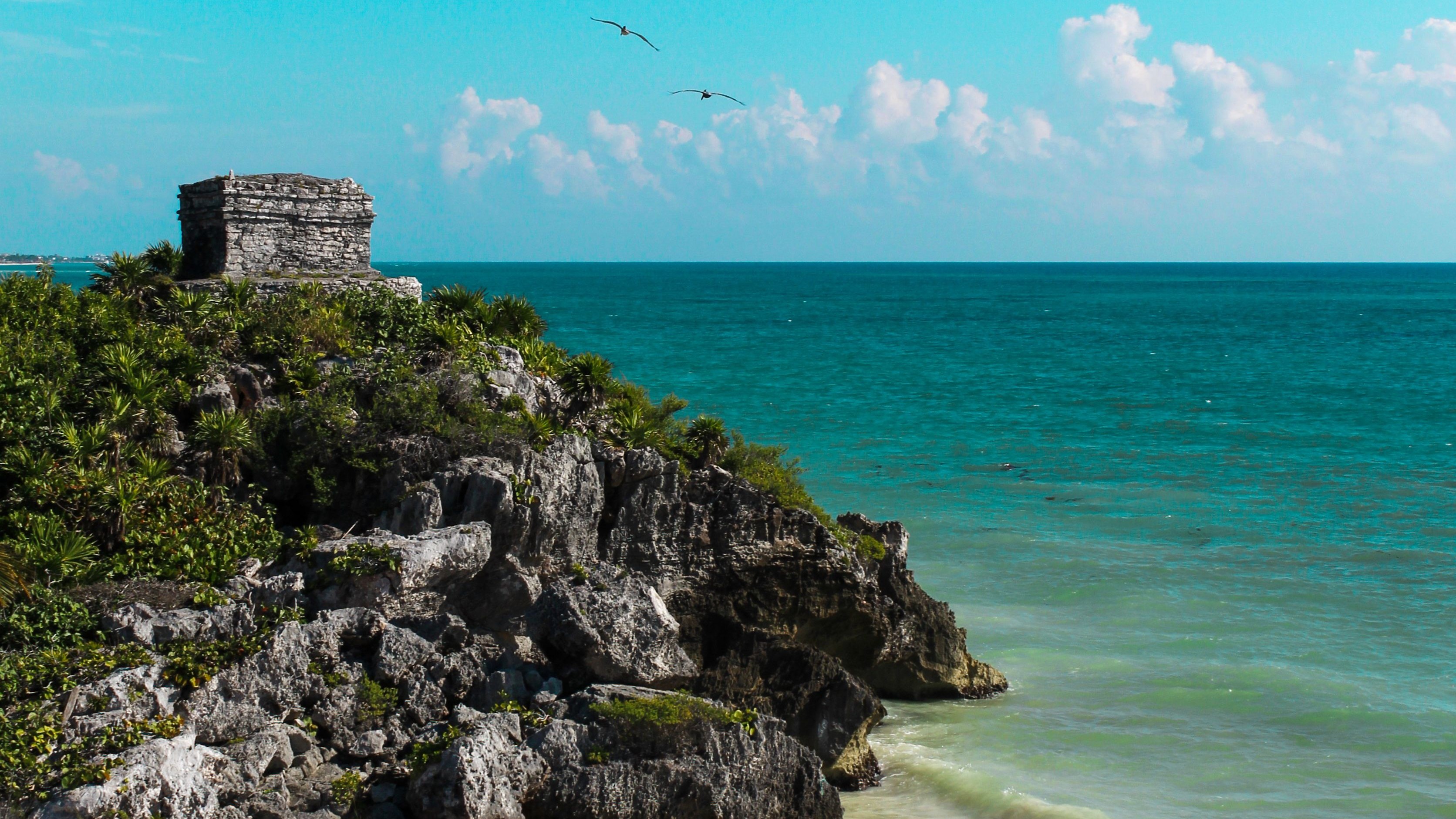El templo maya de Tulum sobre el acantilado, con el Caribe a la derecha y la playa al pie de la roca.